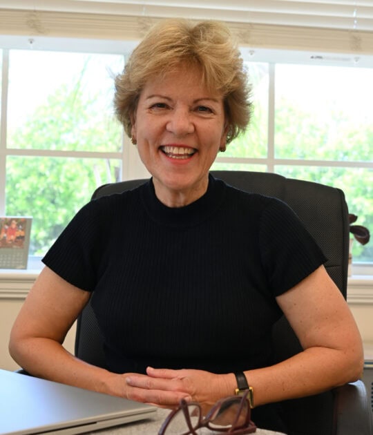 P m draper at desk smiling